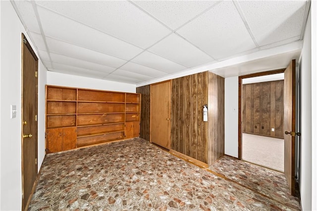 spare room with a paneled ceiling and wood walls