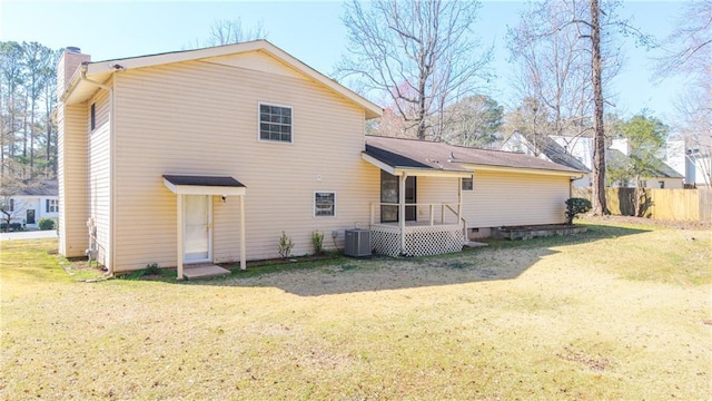 rear view of house featuring a yard, fence, cooling unit, and a chimney