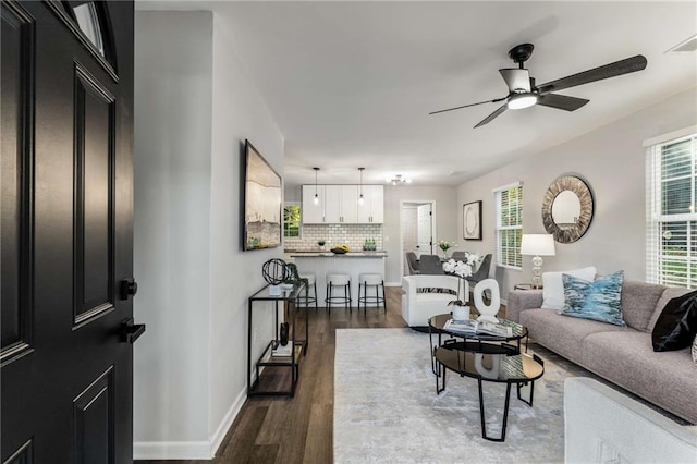 living room with dark wood-style floors, ceiling fan, and baseboards