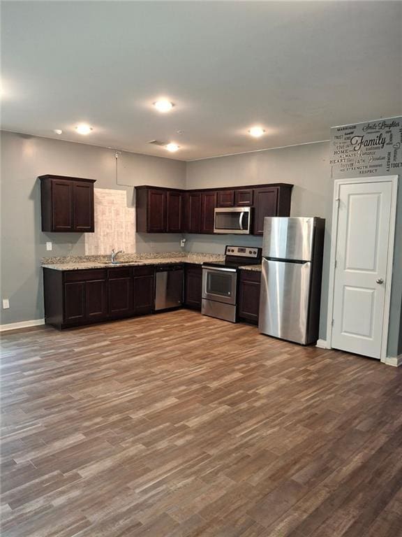 kitchen with dark brown cabinets, stainless steel appliances, and light wood-type flooring