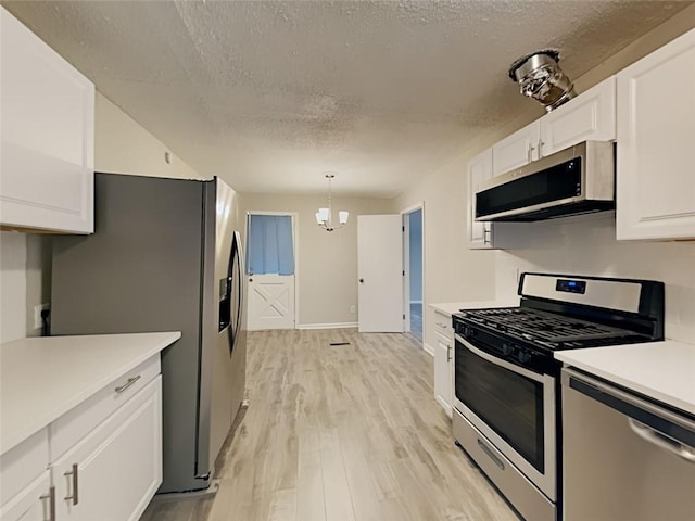 908 Kennesaw Dr, Forest Park, GA 30297 - kitchen featuring stainless steel appliances, a textured ceiling, white cabinetry, light countertops, and light wood-type flooring