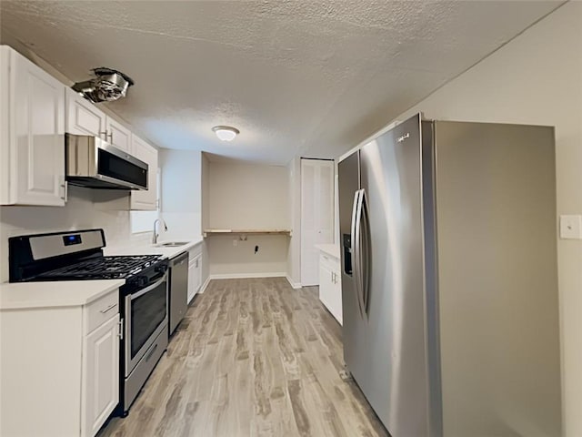 908 Kennesaw Dr, Forest Park, GA 30297 - kitchen with stainless steel appliances, light wood-style flooring, a textured ceiling, white cabinets, and light countertops
