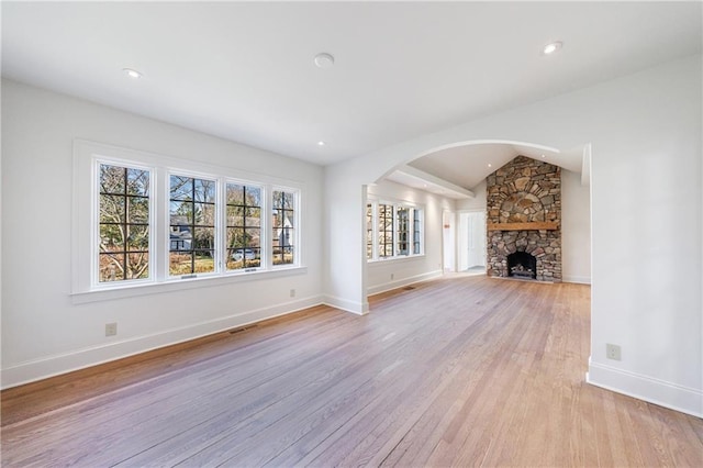 unfurnished living room with a fireplace, light hardwood / wood-style flooring, and lofted ceiling