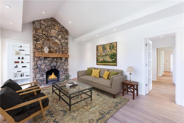 living room with built in shelves, vaulted ceiling, a fireplace, and light hardwood / wood-style flooring