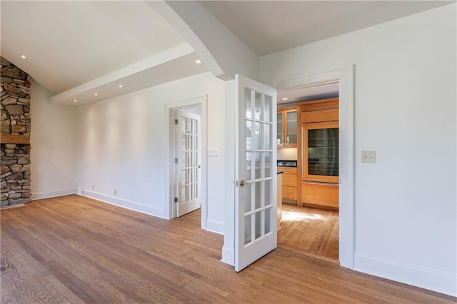 spare room featuring french doors and light hardwood / wood-style flooring