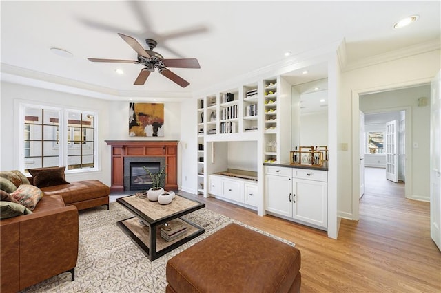 living room featuring light wood-type flooring, plenty of natural light, ornamental molding, and ceiling fan