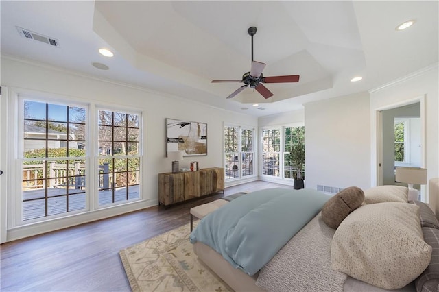 bedroom featuring a raised ceiling, ceiling fan, hardwood / wood-style floors, and ornamental molding