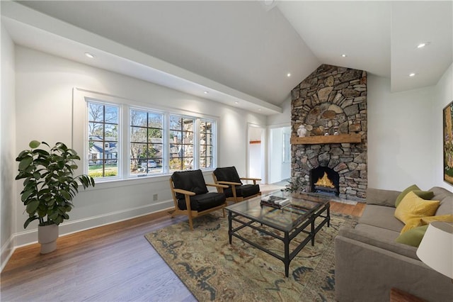 living room featuring hardwood / wood-style flooring, a stone fireplace, and lofted ceiling