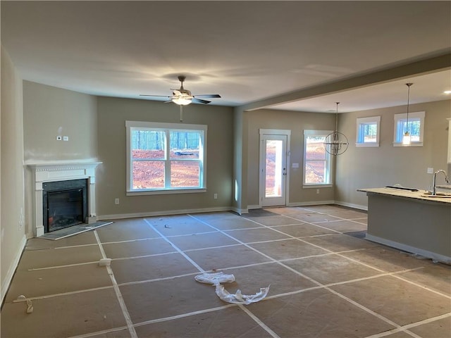 258 Westminster Ct, Winder, GA 30680 - unfurnished living room featuring a sink, baseboards, a fireplace with raised hearth, ceiling fan, and tile patterned floors