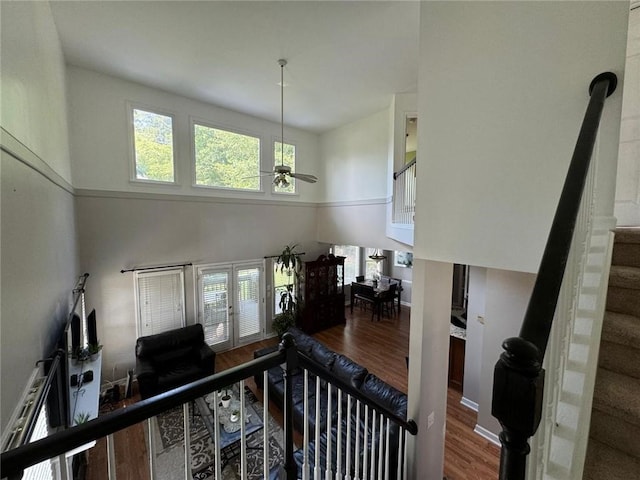 interior space with ceiling fan, a towering ceiling, baseboards, and wood finished floors