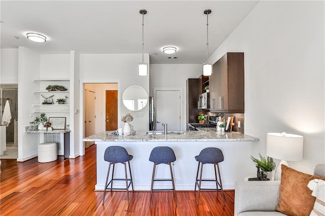 kitchen with kitchen peninsula, decorative light fixtures, stainless steel appliances, built in features, and sink