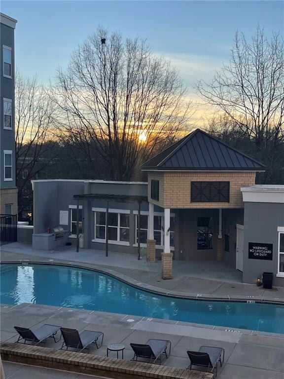 pool at dusk featuring a patio