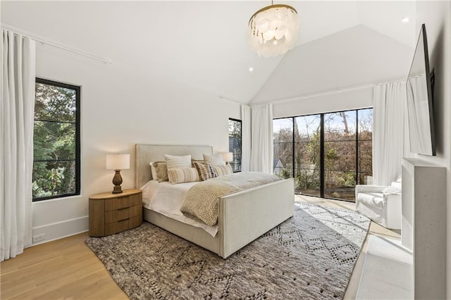 bedroom featuring baseboards, access to exterior, light wood-style floors, high vaulted ceiling, and a notable chandelier