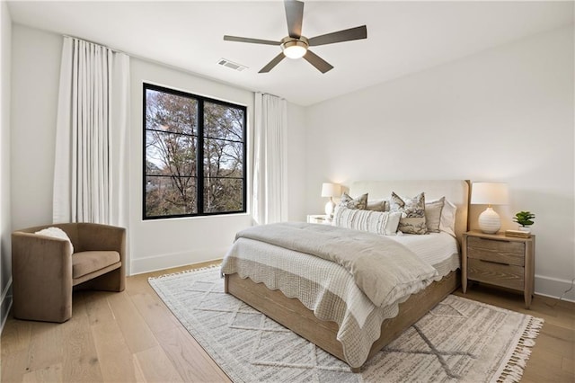 bedroom with baseboards, light wood-type flooring, visible vents, and a ceiling fan