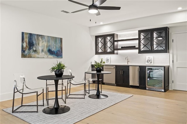 bar featuring indoor wet bar, visible vents, light wood-style floors, beverage cooler, and dishwasher