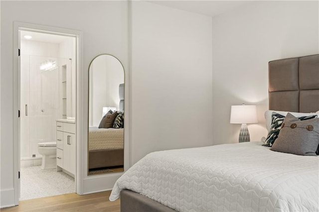 bedroom featuring connected bathroom and light wood-style flooring