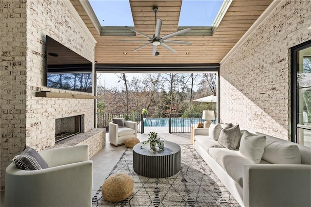 interior space featuring a skylight, a towering ceiling, wood ceiling, a wall of windows, and an outdoor brick fireplace