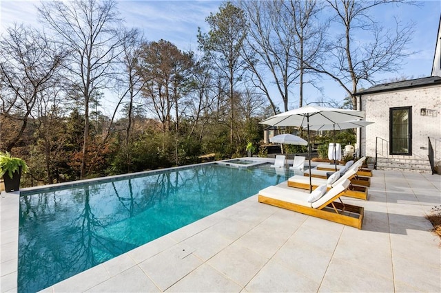 outdoor pool with a patio and an in ground hot tub