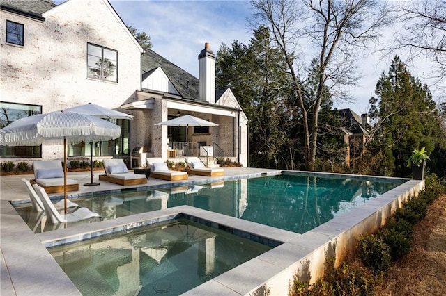 outdoor pool with a patio and an in ground hot tub