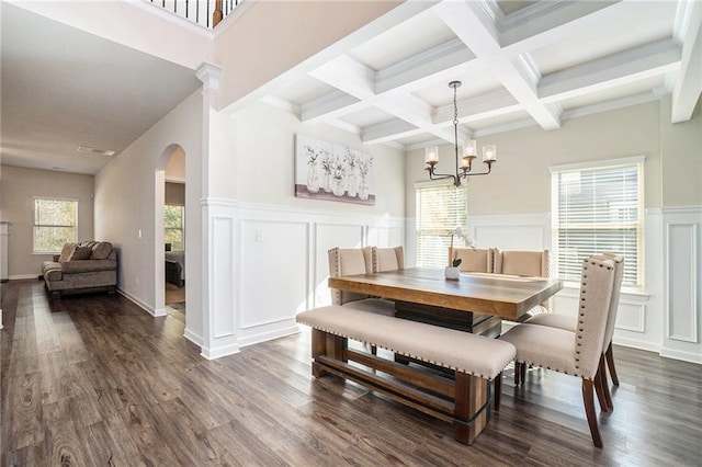 dining room with arched walkways, dark wood finished floors, a decorative wall, and beamed ceiling
