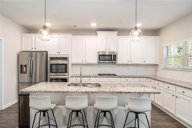 kitchen featuring backsplash, white cabinetry, stainless steel appliances, and a sink