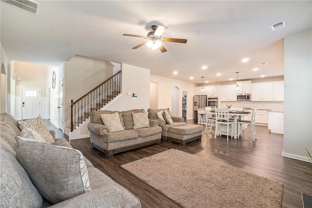 living area featuring stairway, arched walkways, a ceiling fan, and visible vents