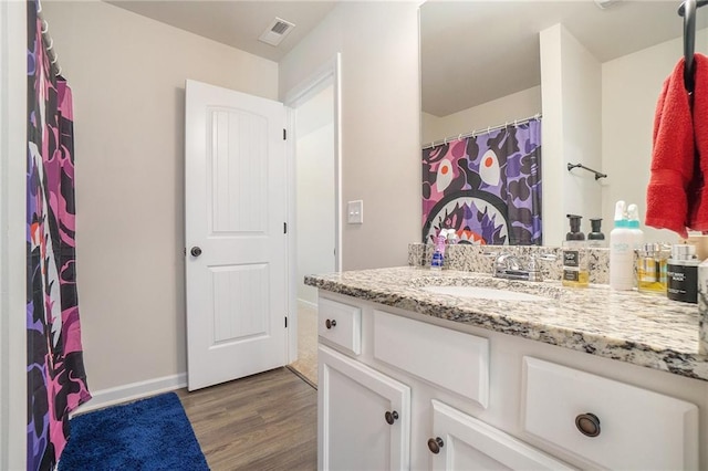 full bathroom with baseboards, wood finished floors, visible vents, and vanity