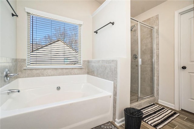 bathroom featuring baseboards, a garden tub, wood finished floors, and a shower stall