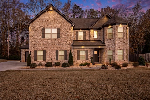 traditional-style home featuring brick siding, fence, a yard, and driveway