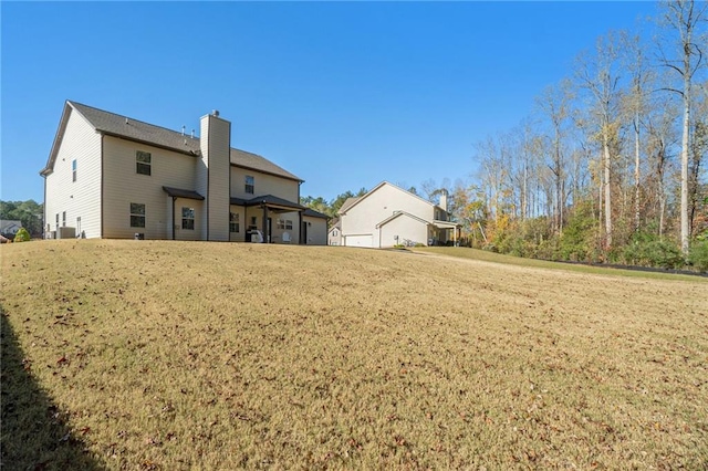 rear view of property featuring a lawn and a chimney