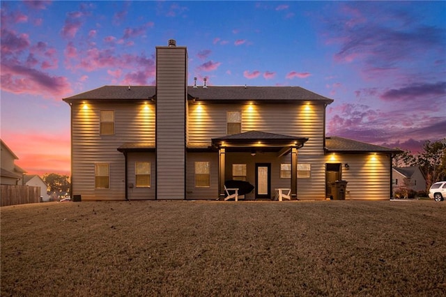 back of house at dusk with a chimney