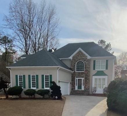 view of front of house featuring a garage, stone siding, concrete driveway, and stucco siding