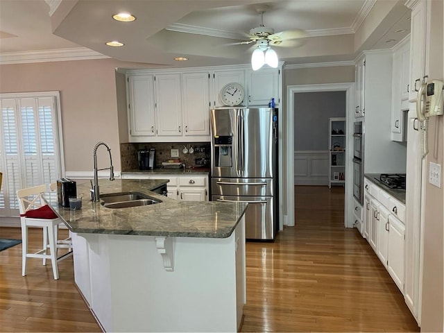 kitchen featuring stainless steel fridge, light wood-style flooring, ornamental molding, and a sink