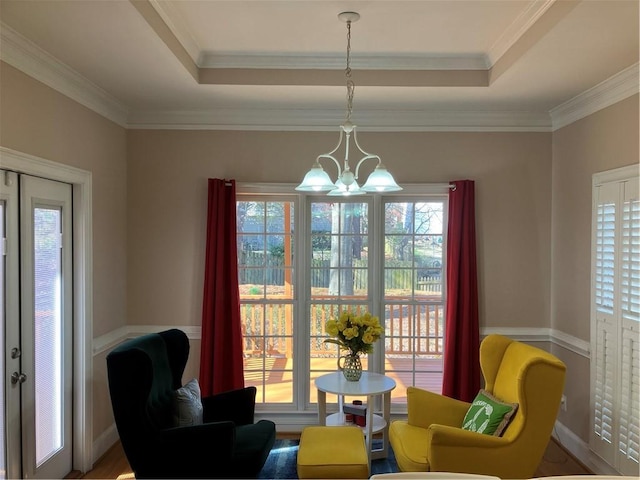 living area with french doors, a raised ceiling, a notable chandelier, and ornamental molding