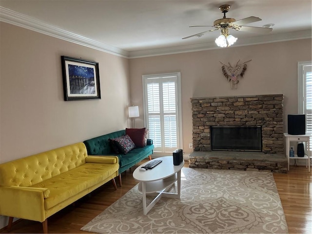 living area with a ceiling fan, wood finished floors, a fireplace, and ornamental molding