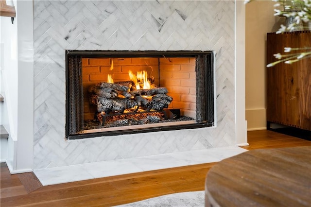 room details featuring baseboards, a fireplace with flush hearth, and wood finished floors