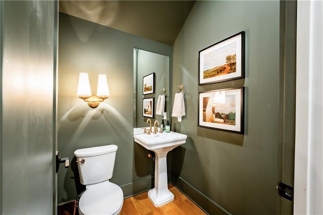 bathroom with toilet, baseboards, and wood finished floors