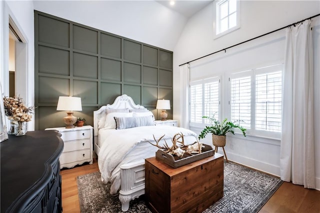 bedroom featuring vaulted ceiling, light wood-style flooring, and multiple windows