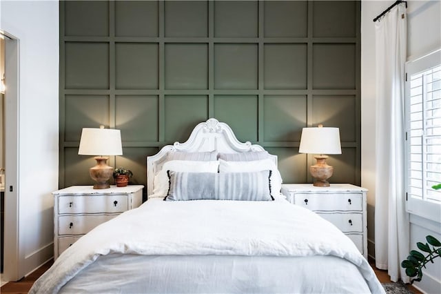 bedroom with a decorative wall and multiple windows