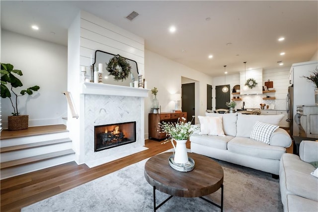 living area featuring recessed lighting, wood finished floors, visible vents, and a premium fireplace