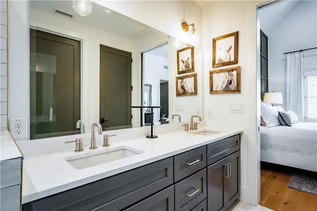 bathroom with a sink, visible vents, wood finished floors, and ensuite bath