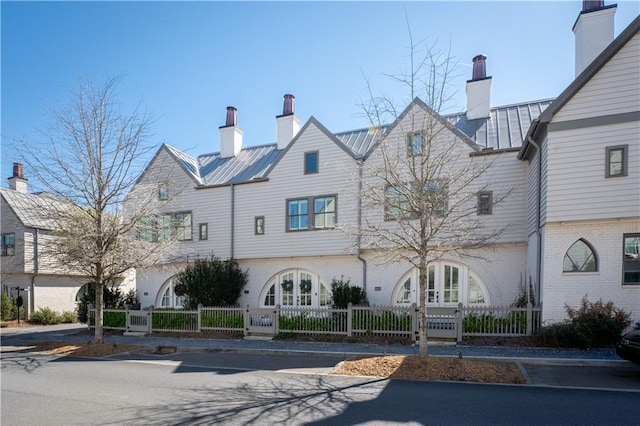 view of front facade with a standing seam roof, french doors, a fenced front yard, and metal roof