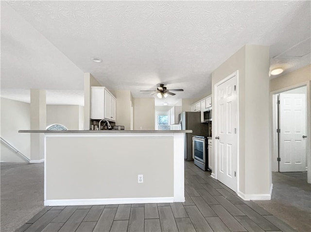 kitchen with ceiling fan, a textured ceiling, white cabinets, and appliances with stainless steel finishes