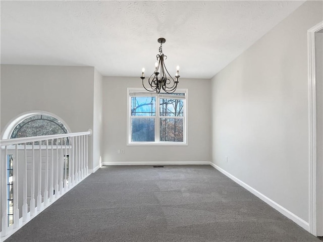 empty room with an inviting chandelier and dark colored carpet