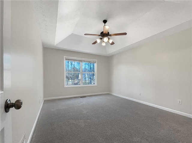 carpeted spare room featuring ceiling fan and a tray ceiling