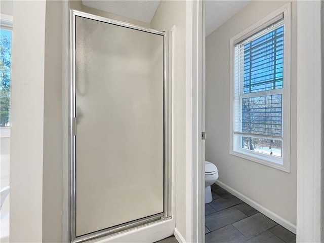 bathroom featuring a shower with shower door and toilet