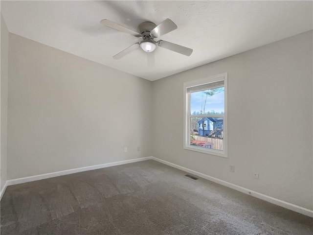 spare room featuring dark carpet and ceiling fan