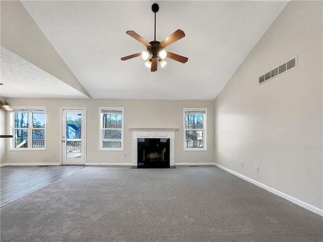 unfurnished living room with ceiling fan, a healthy amount of sunlight, and dark carpet