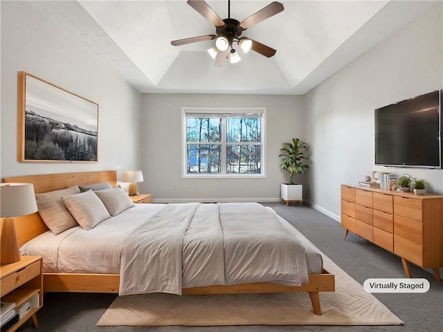 carpeted bedroom with a raised ceiling, lofted ceiling, and ceiling fan