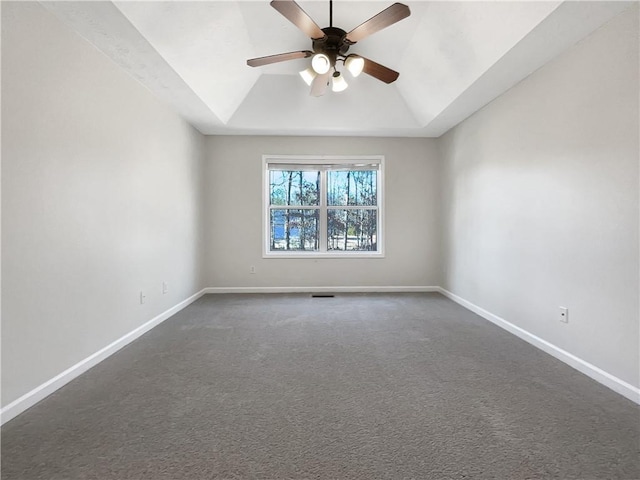 spare room featuring lofted ceiling, a raised ceiling, ceiling fan, and dark colored carpet